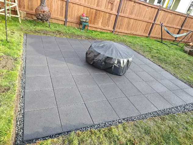 Professional patio installation with dark gray pavers and decorative gravel edging